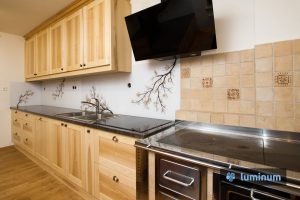 Kuhinjsko steklo z motivom veje z rjavimi listi, ki se barvno ujema z masivno leseno kuhinjo in vgrajenim štedilnikom