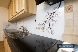 Kuhinjsko steklo z motivom veje z rjavimi listi, ki se barvno ujema z masivno leseno kuhinjo in vgrajenim štedilnikom