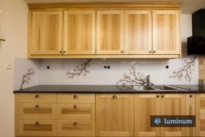 Kuhinjsko steklo z motivom veje z rjavimi listi, ki se barvno ujema z masivno leseno kuhinjo in vgrajenim štedilnikom