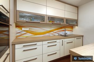 Natančna montaža kuhinjske steklene obloge za zaščito stene v kuhinji z živahnimi oranžnimi vijugami