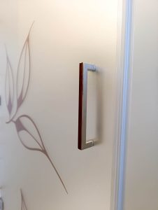 Detajl ročaja steklene tuš kabine Luminum z matiranim steklom in dekorativnim motivom listov